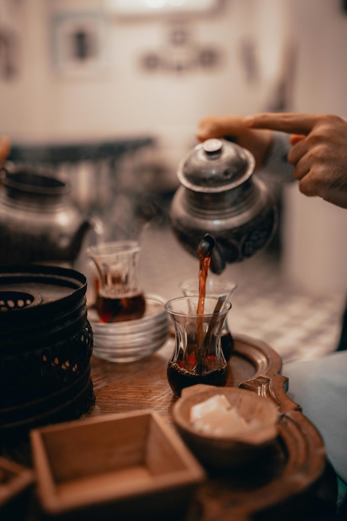 Crop person pouring tea from old teapot into glass